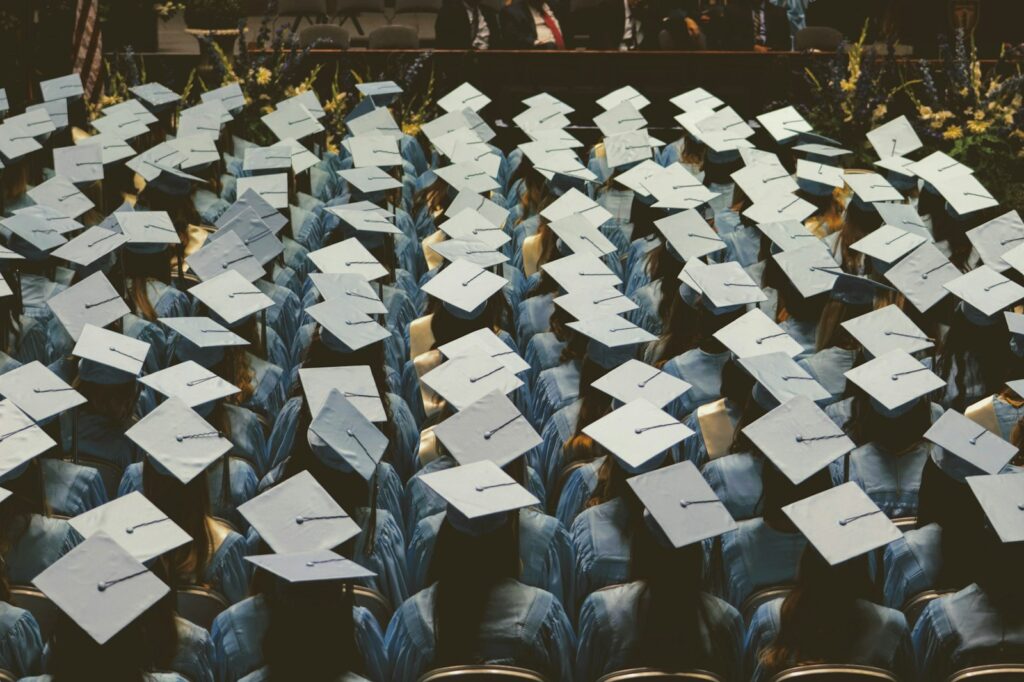 Para wisudawan berjubah biru muda dan bertopi toga di upacara wisuda