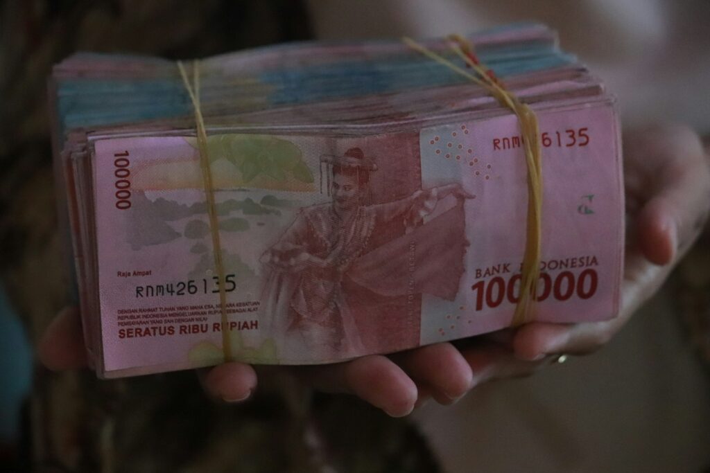 Tangan memegang uang kertas rupiah
